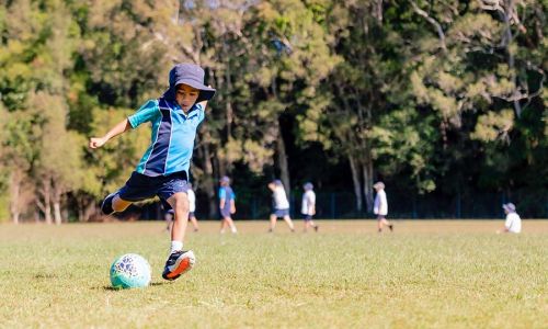 Junior School student kicking soccer ball